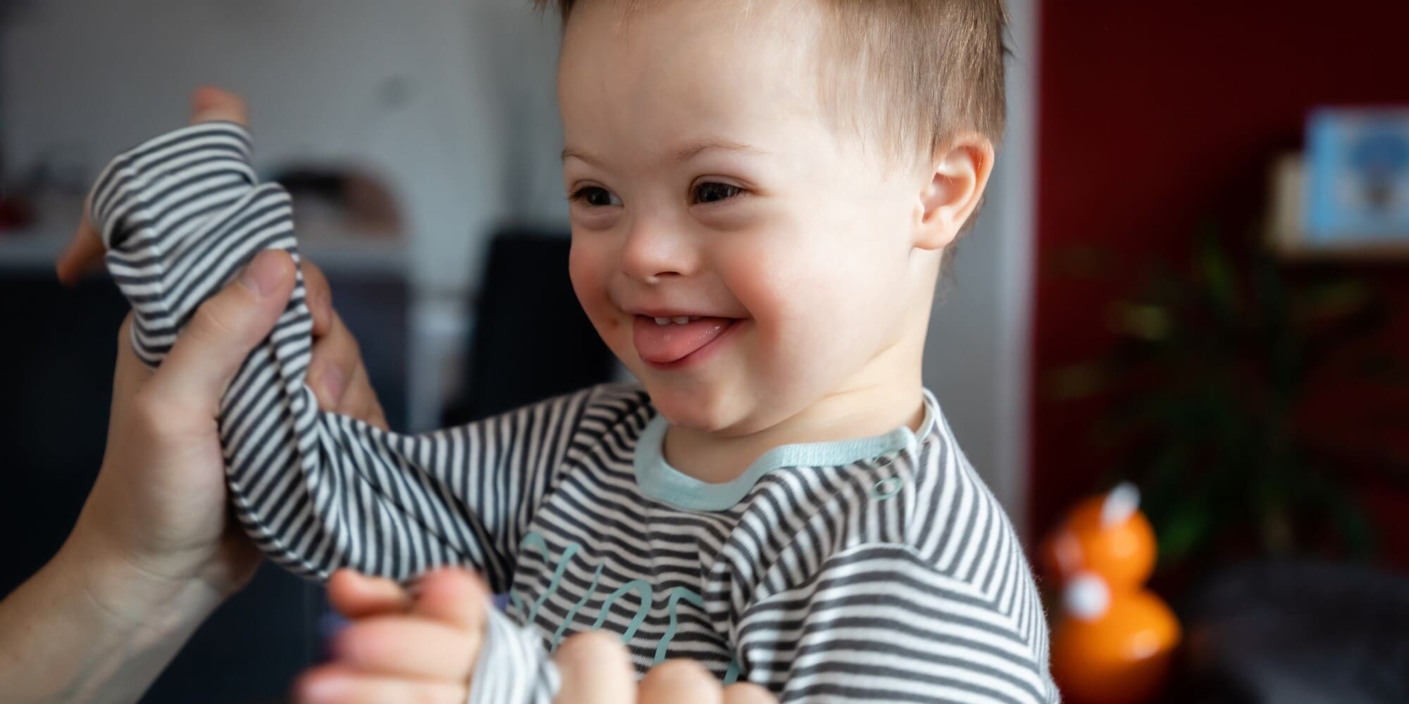 Cute boy with Down syndrome playing with dad on in home living room