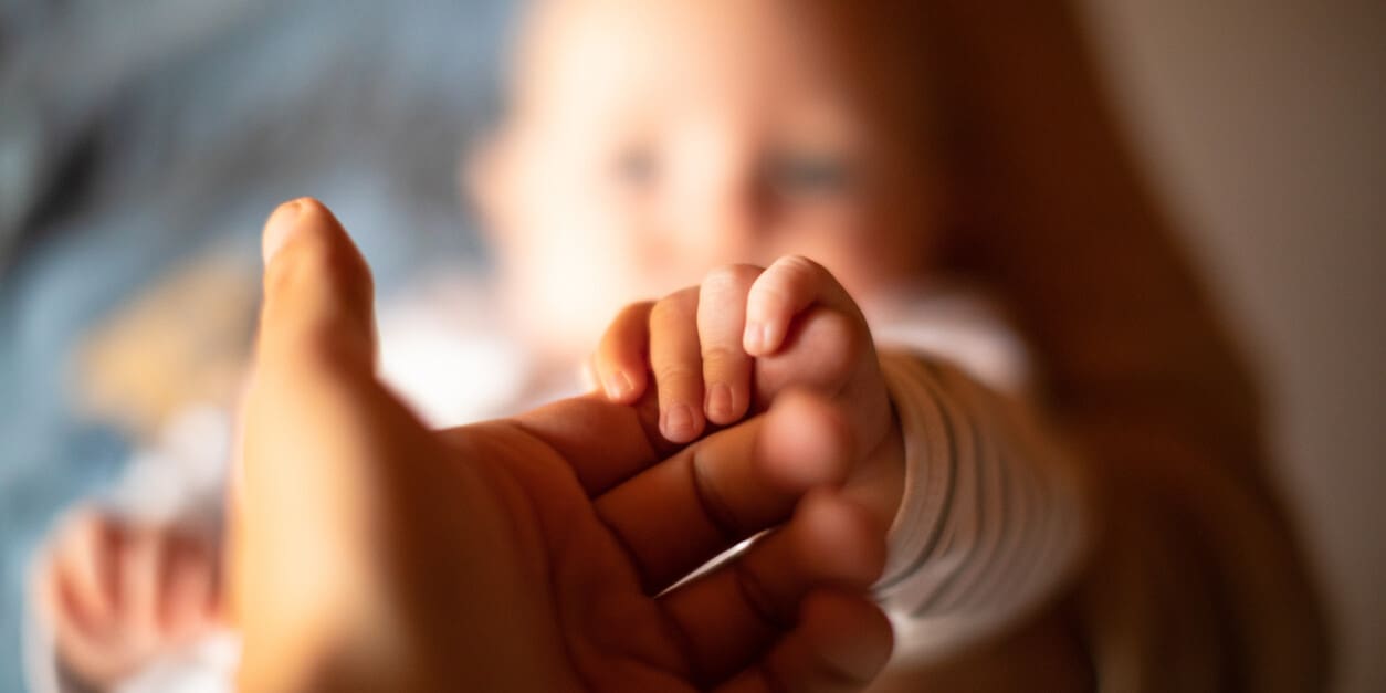 Hand holding newborn baby's hand